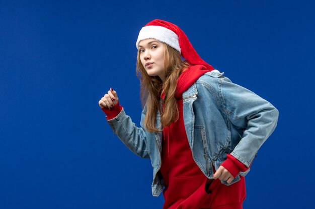 Vorderansicht junge Frau mit roter Weihnachtsmütze auf blauem Hintergrund Emotion Weihnachtsfeiertag