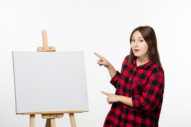 Vorderansicht junge Frau mit Staffelei zum Zeichnen auf weiße Wand