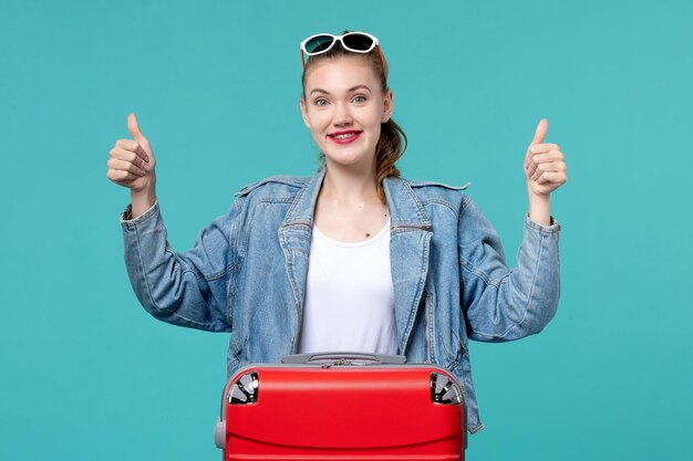 Vorderansicht junge Frau mit Tasche, die für Urlaub auf dem blauen Raum vorbereitet