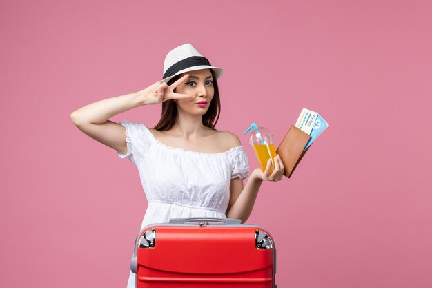 Vorderansicht junge Frau mit Tickets für den Urlaub und posiert auf hellrosa Wand Sommerreise Emotion Flugzeug Reise