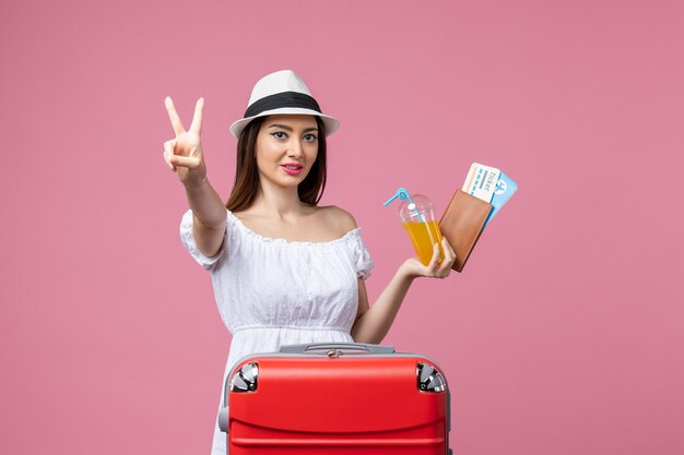 Vorderansicht junge Frau mit Tickets für den Urlaub und posiert auf rosa Wand Sommer Reise Emotionen Flugzeug Reise