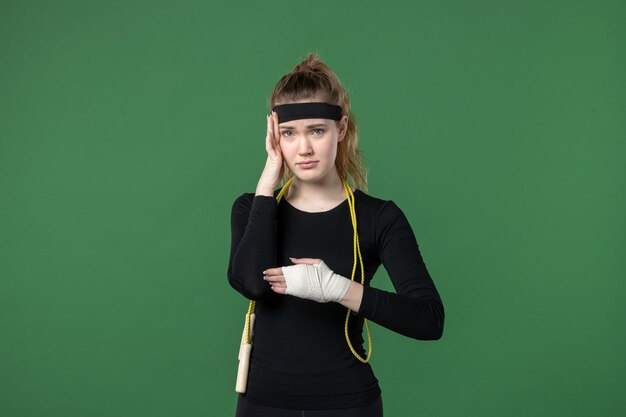 Vorderansicht junge Frau mit Verband um ihren verletzten Arm auf grünem Hintergrund Athlet Schmerzen Gesundheit Verletzung Frau Sport Workout Körperfarben