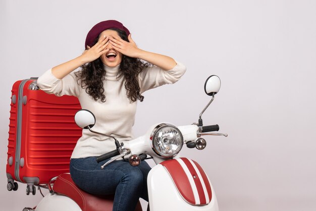 Vorderansicht junge Frau sitzt auf dem Fahrrad und bedeckt ihr Gesicht auf weißem Hintergrund Frau Fahrzeuggeschwindigkeit Urlaub Motorrad Straße Stadt Farbe