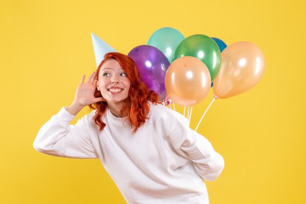 Vorderansicht junge Frau versteckt bunte Luftballons hinter ihrem Rücken Farbe Neujahr Emotionen Party Weihnachtsfrau