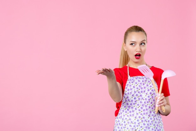 Kostenloses Foto vorderansicht junge hausfrau mit besteck an rosa wand