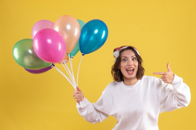 Vorderansicht junge hübsche Frau, die Luftballons auf gelbe Neujahrs-Emotion-Weihnachtsfarbfrau hält