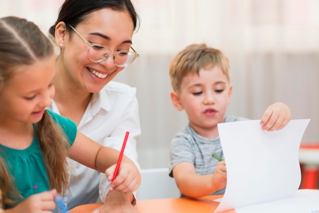 Kostenloses Foto vorderansicht junge lehrerin hilft ihren schülern in der klasse