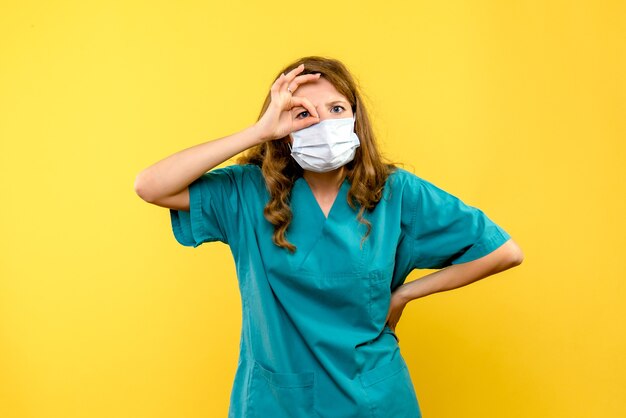 Vorderansicht junge Ärztin in Maske auf gelbem Raum