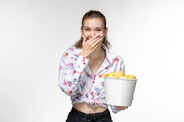 Vorderansicht junge schöne weibliche Haltekorb mit Kartoffelspitzen, die Film ansehen und auf weißer Oberfläche lachen