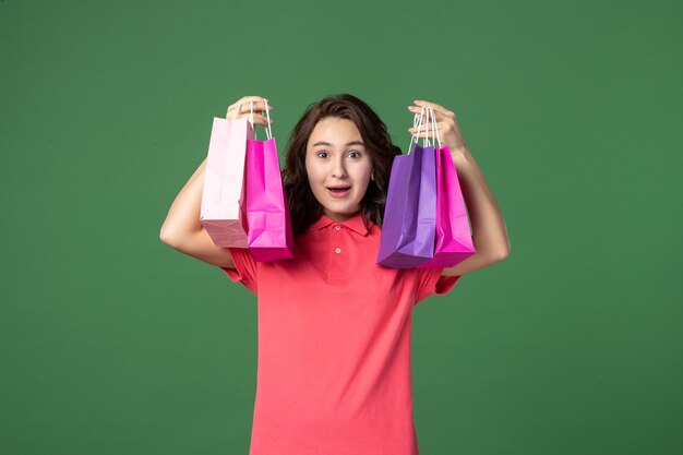 Vorderansicht junge Verkäuferin mit kleinen Paketen auf grünem Hintergrund Farbe Shopping Job Arbeiter Boutique Verkauf