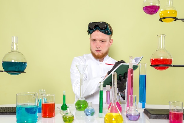 Vorderansicht junger Chemiker, der einige Notizen über Chemikalien macht