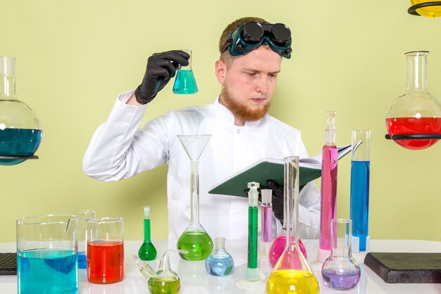 Vorderansicht junger Chemiker, der über hellblaue Chemikalie liest