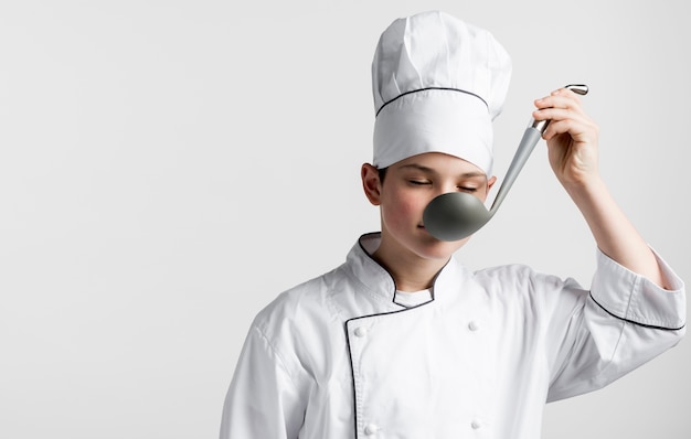 Kostenloses Foto vorderansicht junger koch, der suppenkelle schmeckt