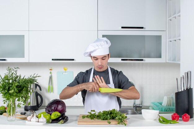 Vorderansicht junger Koch in Uniform mit Blick auf Messer
