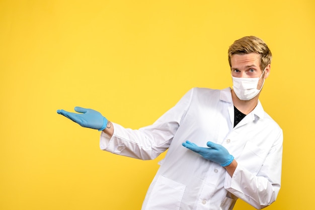 Vorderansicht junger männlicher Arzt auf gelbem Hintergrund Pandemie Sanitäter Gesundheit Covid