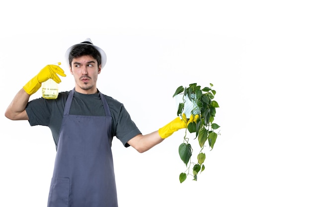 Vorderansicht junger männlicher Gärtner, der Pflanze im Topf hält und auf weißem Hintergrund sprüht Blume Arbeit Baum Gras Farbe Boden Job Garten