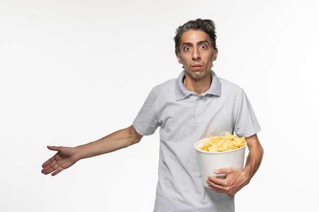 Vorderansicht junger männlicher Haltekorb mit Kartoffelchips auf weißem Schreibtisch