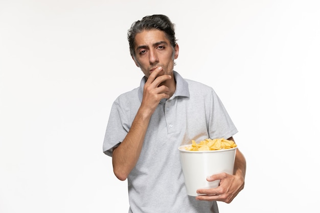 Vorderansicht junger männlicher Haltekorb mit Kartoffelchips, die auf weißer Oberfläche denken