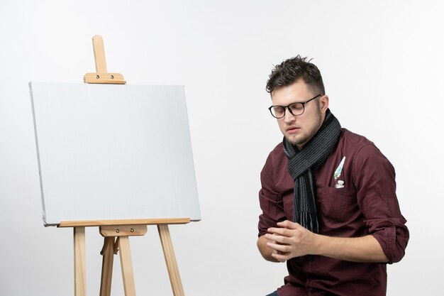 Vorderansicht junger männlicher Maler zusammen mit Staffelei auf weißem Hintergrund