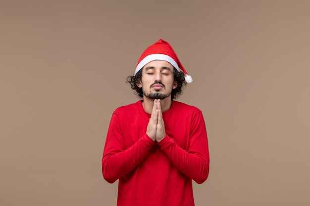 Vorderansicht junger Mann, der auf braunen Hintergrundgefühlen Weihnachtsferien betet