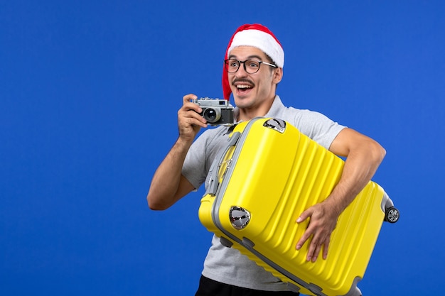 Vorderansicht junger Mann, der Foto mit Kamera auf blauen Wandflügen Urlaubsflugzeuge nimmt