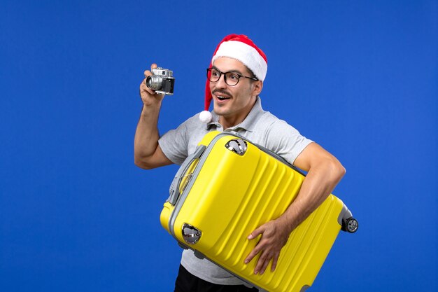 Vorderansicht junger Mann, der Foto mit Kamera auf blauen Wandflügen Urlaubsflugzeuge nimmt