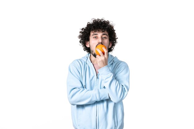 Vorderansicht junger Mann, der frische Orange auf weißem Hintergrund riecht