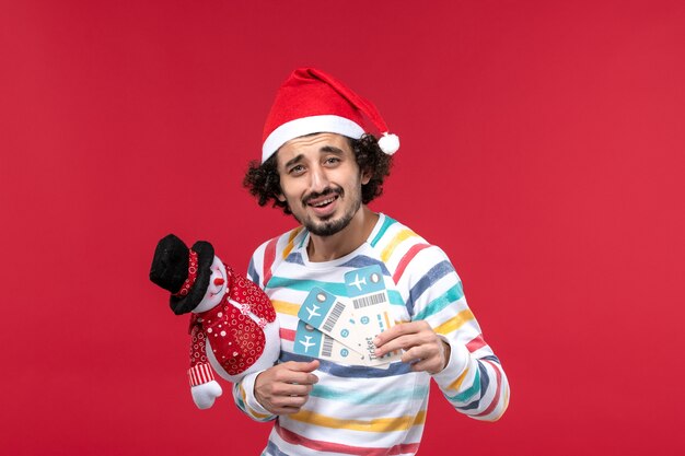 Vorderansicht junger Mann, der Karten und Spielzeug auf rotem Wand männlichem rotem Feiertags-Neujahr hält