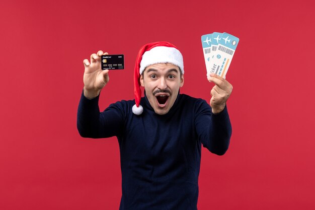 Vorderansicht junger Mann, der Kartenbankkarte auf rotem Hintergrund hält