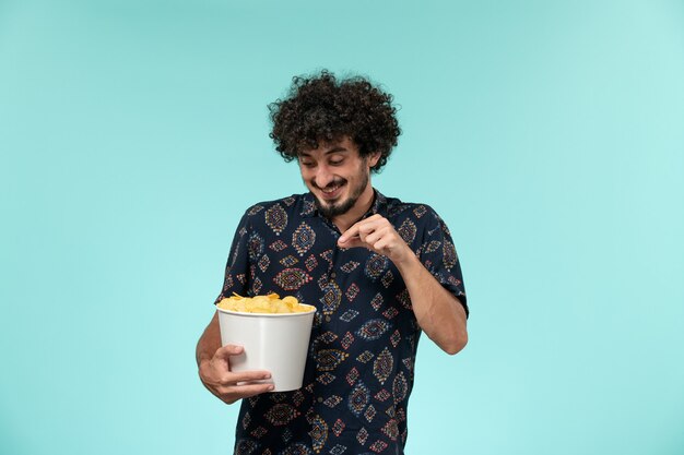 Vorderansicht junger Mann, der Kartoffelspitzen an der blauen Wand Kino Filme Filmtheater männlich hält