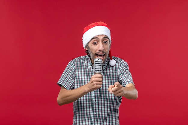 Vorderansicht junger Mann, der Mikrofon auf roter Wandemotionsfeiertags-Sängermusik verwendet
