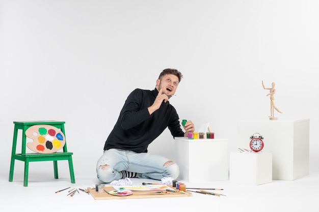 Vorderansicht junger Mann, der mit Farben auf weißer Wand arbeitet Künstler malen Kunst Farbmalerei Bild zeichnen Foto