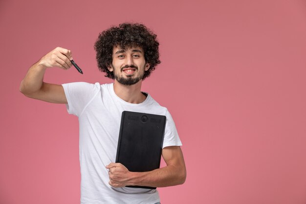 Vorderansicht junger Mann, der mit Stift und Notizbuch aufwirft