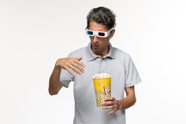 Vorderansicht junger Mann, der Popcorn in d Sonnenbrille auf hellweißer Oberfläche isst