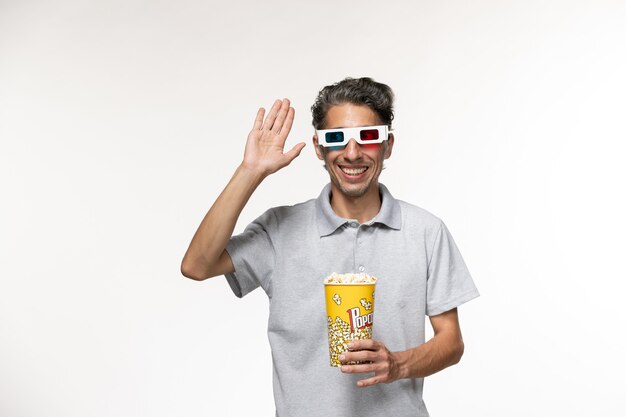 Vorderansicht junger Mann, der Popcorn-Paket in d Sonnenbrillen hält, die auf einer weißen Oberfläche lächeln