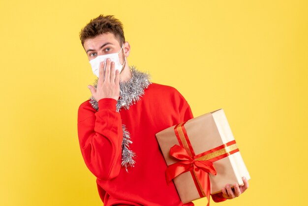 Vorderansicht junger Mann, der Weihnachten in steriler Maske hält