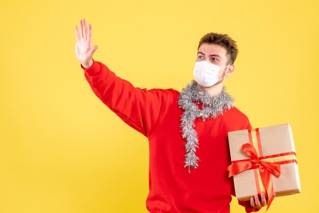 Vorderansicht junger Mann, der Weihnachten in steriler Maske hält