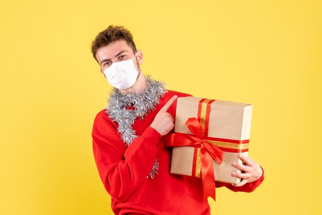 Vorderansicht junger Mann, der Weihnachten in steriler Maske hält