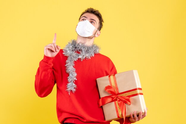 Vorderansicht junger Mann, der Weihnachten in steriler Maske hält