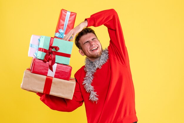 Kostenloses Foto vorderansicht junger mann, der weihnachtsgeschenke hält