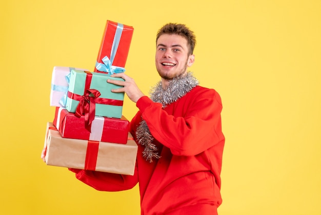 Vorderansicht junger Mann, der Weihnachtsgeschenke hält