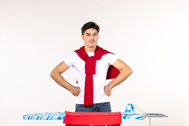 Vorderansicht junger mann hinter bügelbrett auf weißem hintergrund saubere hausarbeit heimarbeit emotion mode kleidung mann