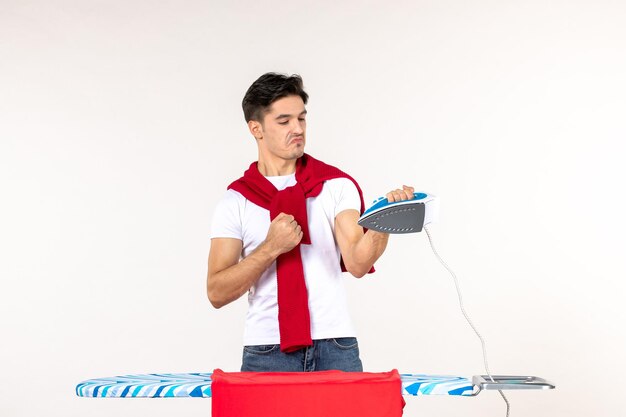 Vorderansicht junger Mann hinter Bügelbrett auf weißem Hintergrund Wäscherei Arbeit Mann nach Hause saubere Hausarbeit