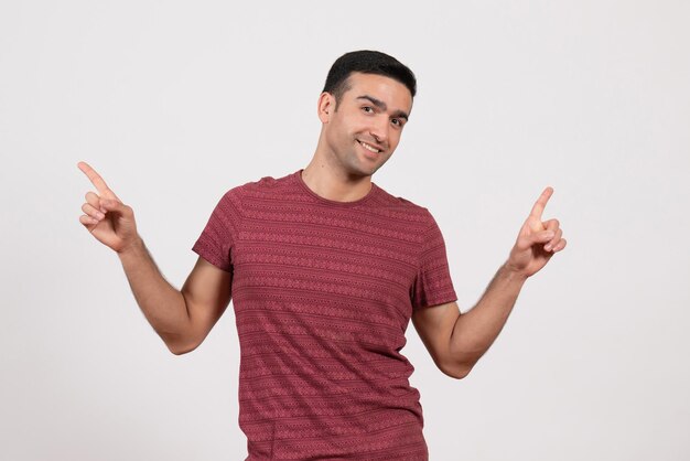 Vorderansicht junger Mann im dunkelroten T-Shirt stehend lächelnd auf weißem Hintergrund