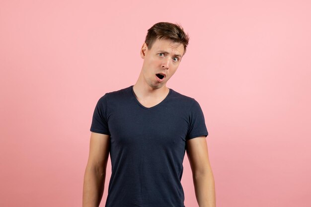 Vorderansicht junger Mann im dunklen T-Shirt mit überraschtem Ausdruck auf rosa Hintergrund