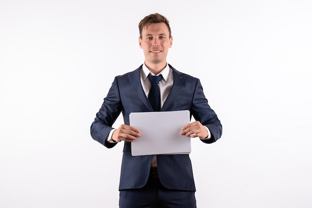 Vorderansicht junger Mann im eleganten klassischen Anzug mit Dokumenten auf weißem Hintergrund