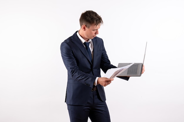 Vorderansicht junger Mann im eleganten klassischen Anzug mit seinem Laptop auf weißem Hintergrund