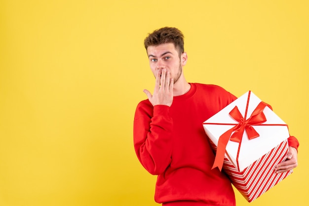 Vorderansicht junger Mann im roten Hemd mit Weihnachtsgeschenk