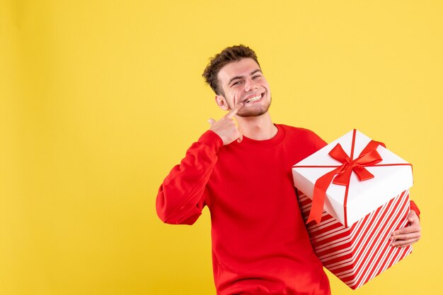 Vorderansicht junger Mann im roten Hemd mit Weihnachtsgeschenk