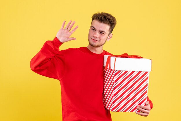 Vorderansicht junger Mann im roten Hemd mit Weihnachtsgeschenk